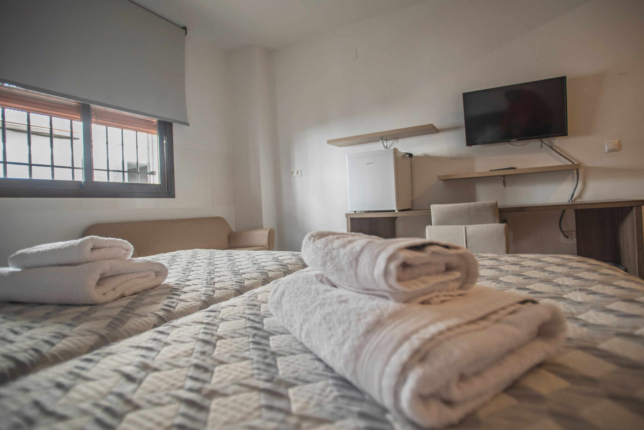 Habitación luminosa y funcional, con camas individuales, ropa de cama cuidada y un espacio sencillo pensado para el descanso.