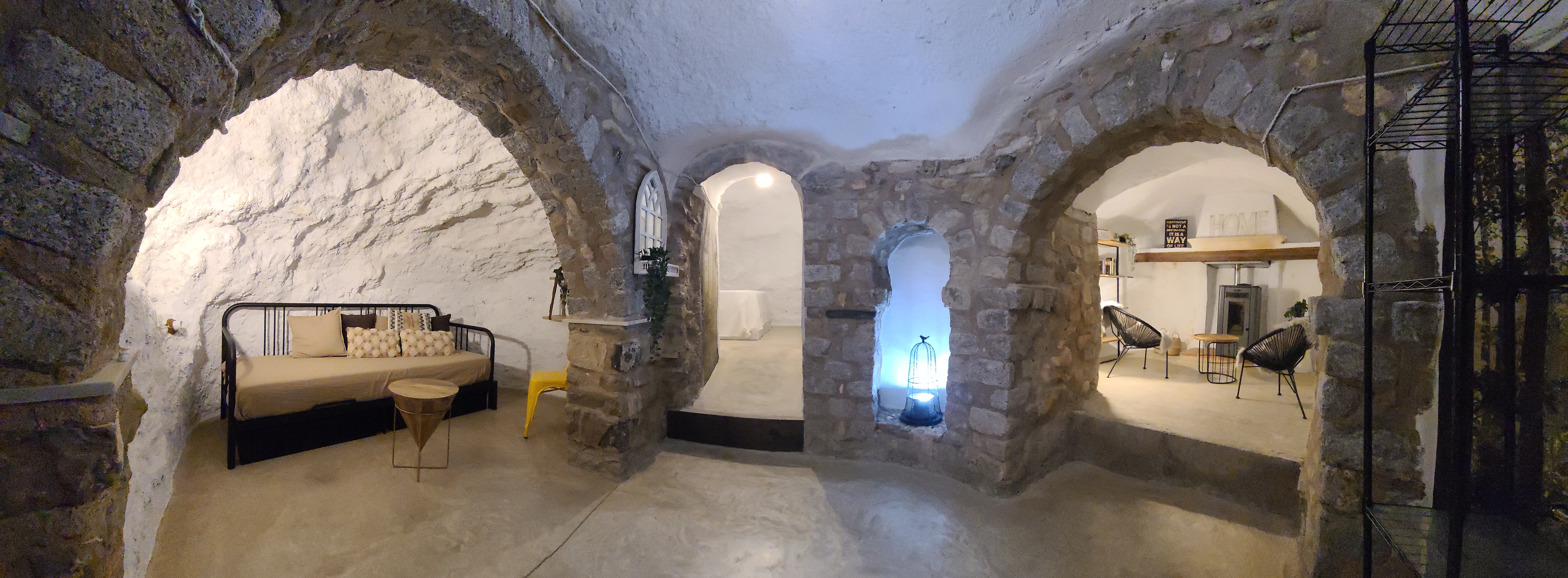 Ambiente singular con arcos de piedra y paredes excavadas, que evocan la arquitectura de cueva tradicional. Los distintos espacios se articulan mediante aberturas que conectan zonas de descanso y estar, creando una sensación acogedora e íntima. La iluminación suave refuerza el carácter cálido y envolvente del lugar.