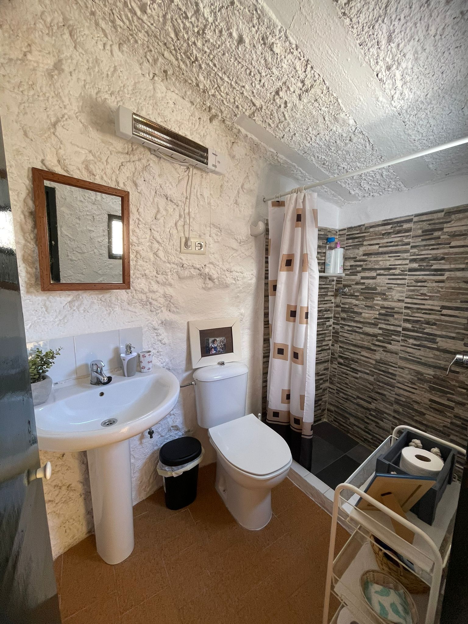 Baño funcional que combina elementos modernos con paredes naturales de la cueva. Un espacio práctico y cuidado, integrado en la estética del alojamiento.
