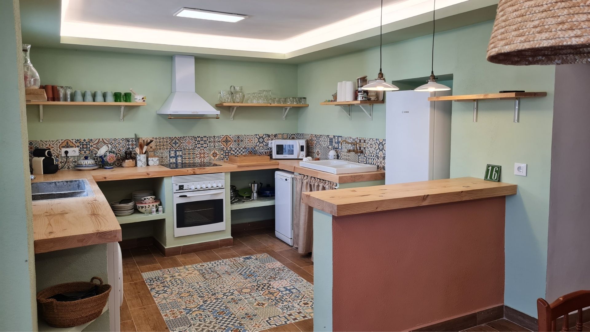 Cocina funcional y bien equipada, con mobiliario de madera, estanterías abiertas y azulejos decorativos. Combina un diseño práctico con un estilo cuidado, pensada para estancias cómodas y autónomas.