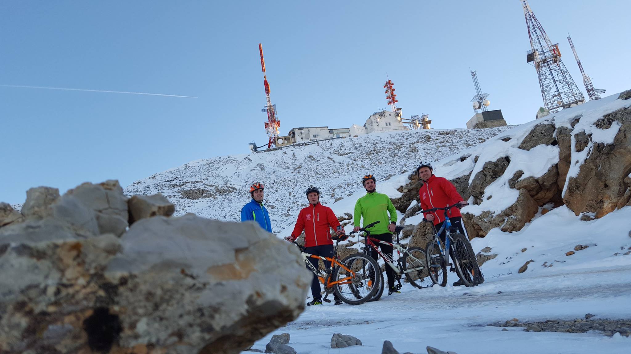 Grupo de ciclistas con bicicletas de montaña en un entorno de alta montaña cubierto de nieve.