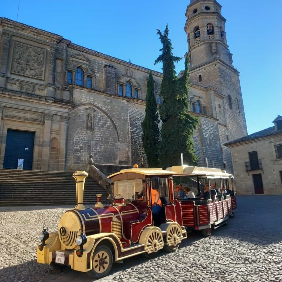 Tren turístico frente a un conjunto monumental, preparado para recorrer el casco histórico.