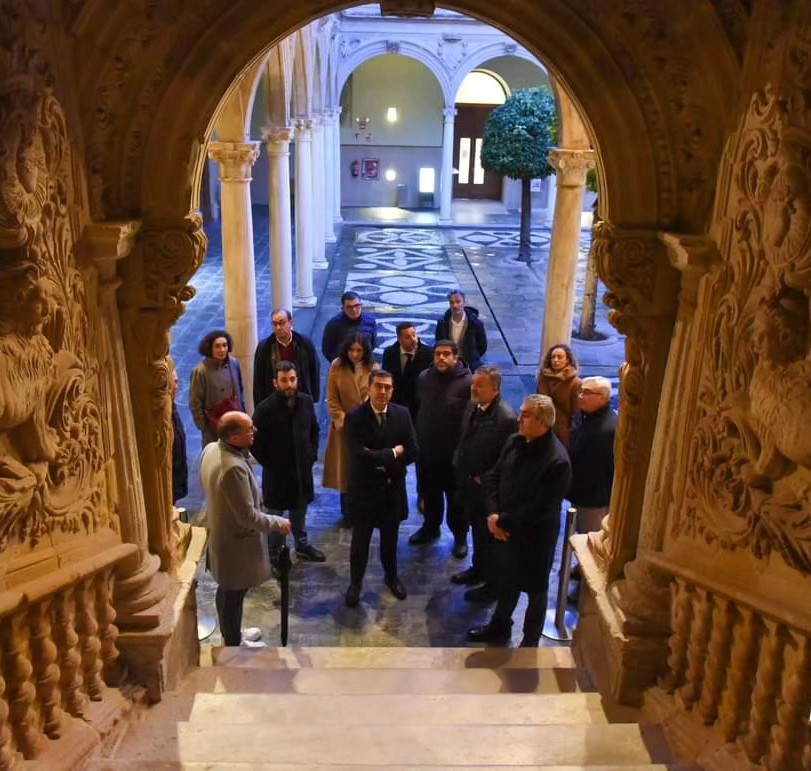 Grupo de personas atendiendo las explicaciones de un guía en el interior de un espacio histórico.