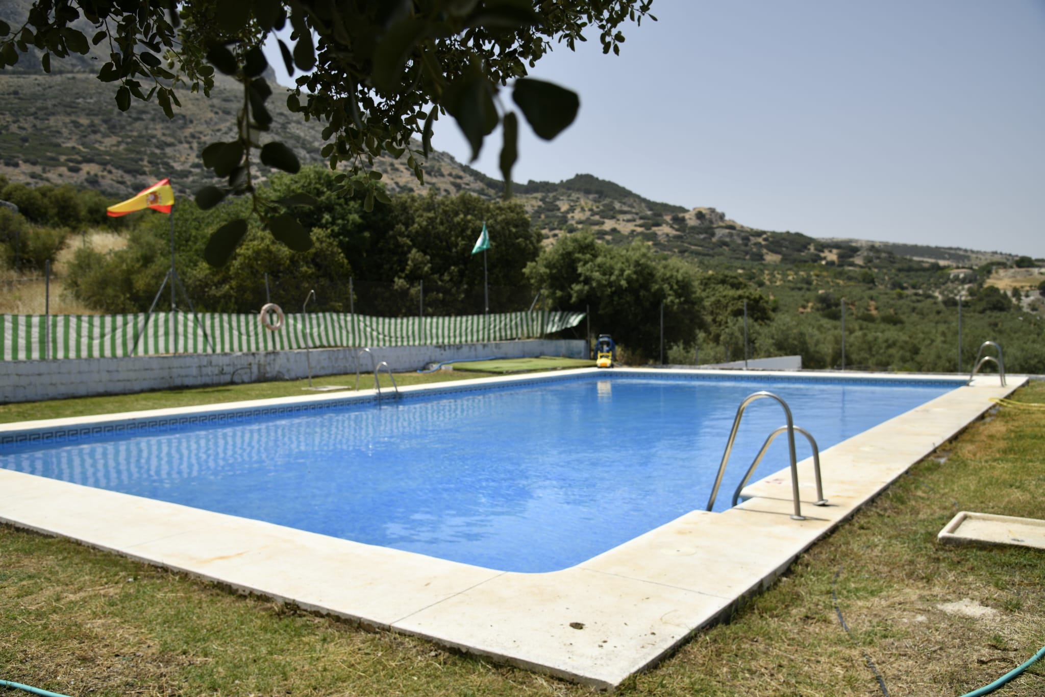 Piscina rectangular al aire libre con vistas abiertas al paisaje de Sierra Mágina. Al fondo se aprecian lomas cubiertas de olivares y monte bajo, lo que refuerza la sensación de estar en plena naturaleza. Un espacio pensado para refrescarse y disfrutar del entorno en los meses más cálidos.