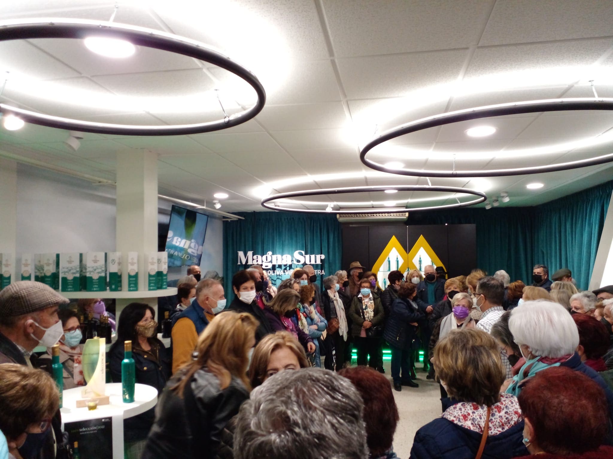 Grupo numeroso de personas en un espacio interior observando productos y atendiendo a una explicación durante la visita.