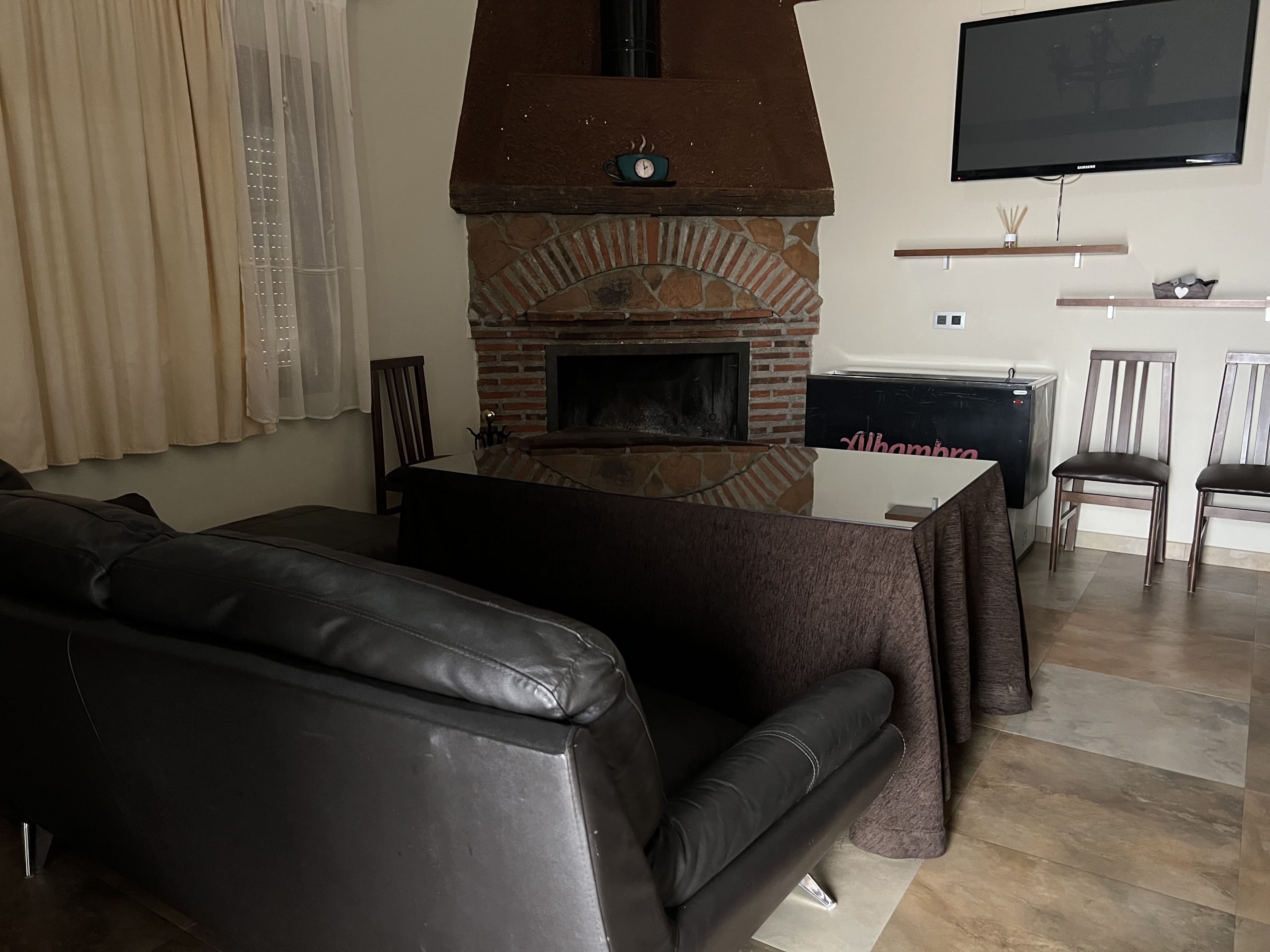 Sala de estar acogedora con chimenea de obra, sofá y mobiliario sencillo en un ambiente cálido y tradicional.