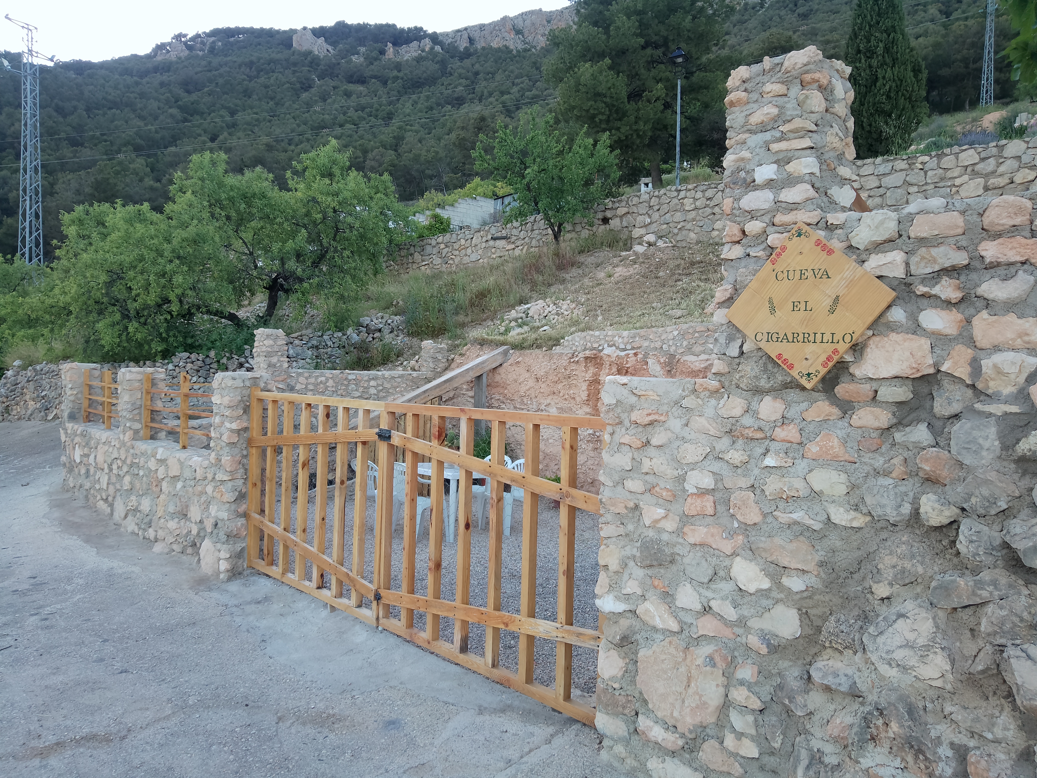 Entrada al alojamiento con cerramiento de piedra y madera, integrada en el paisaje de sierra. El entorno natural y las vistas aportan carácter y conexión con el territorio.