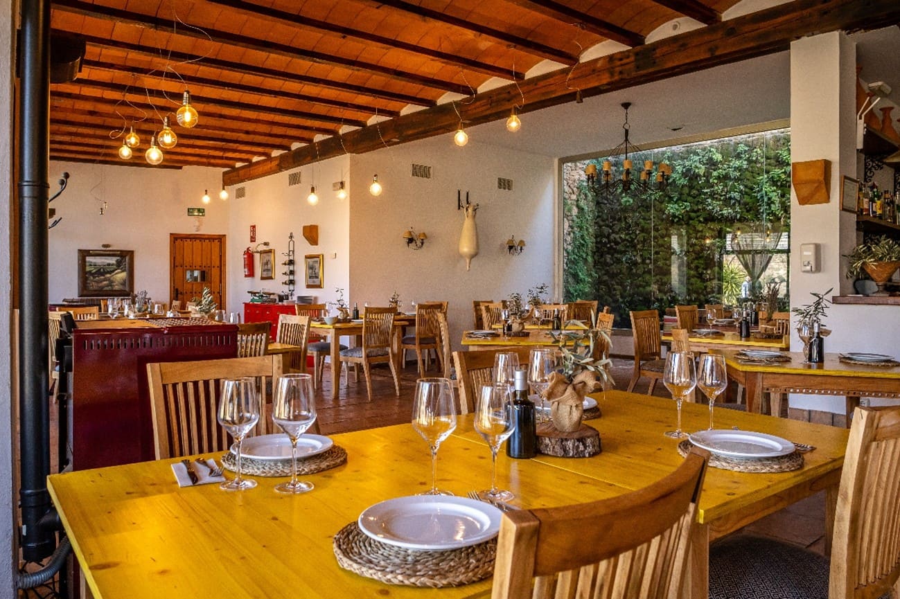 Comedor interior de restaurante rural con mesas preparadas, iluminación cálida y decoración tradicional.