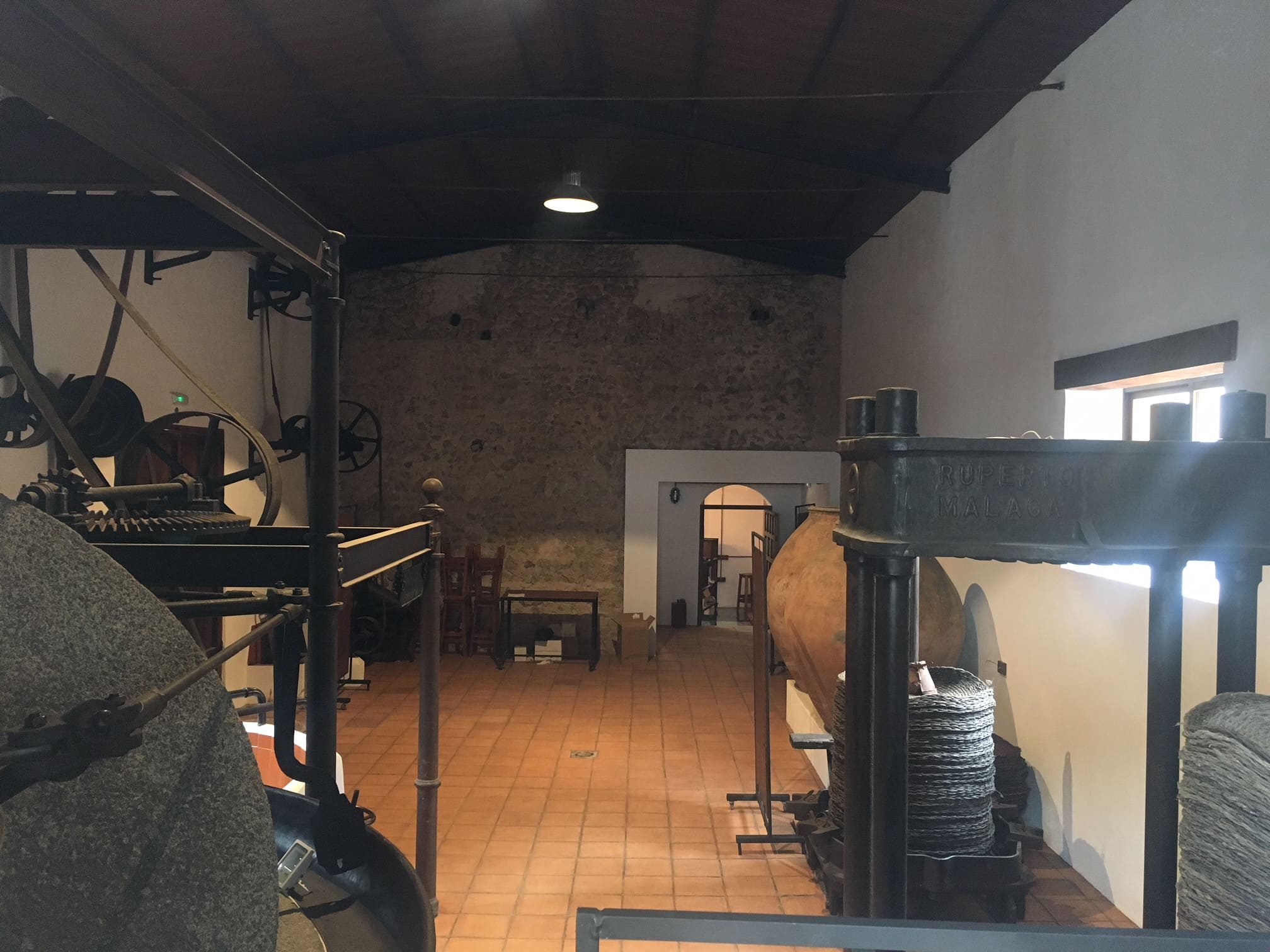 Espacio interior con maquinaria histórica de molienda, donde se observan prensas y elementos tradicionales utilizados en la producción de aceite.