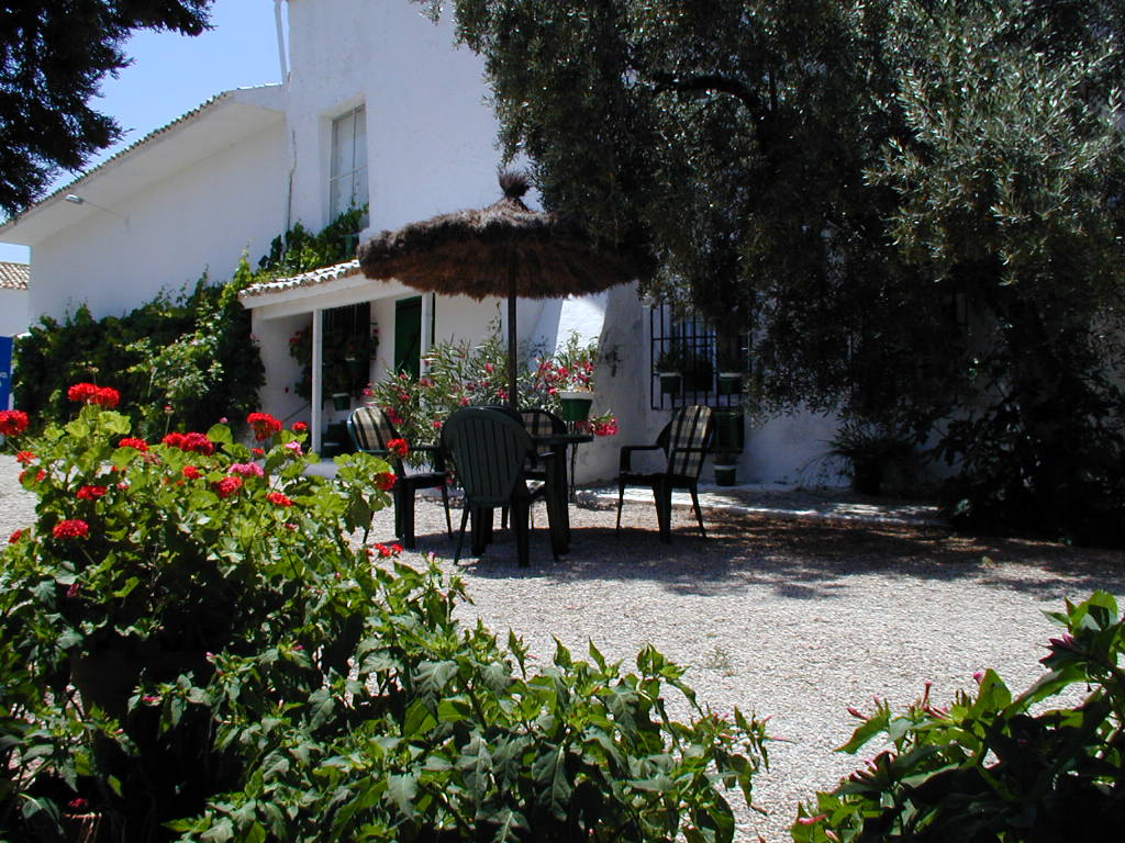 Espacio exterior ajardinado con zona de descanso al aire libre, equipado con mesa, sillas y sombrilla. Rodeado de vegetación y flores, este rincón transmite tranquilidad y conexión con el entorno. Ideal para disfrutar de comidas, lecturas o momentos de relax en un ambiente natural.