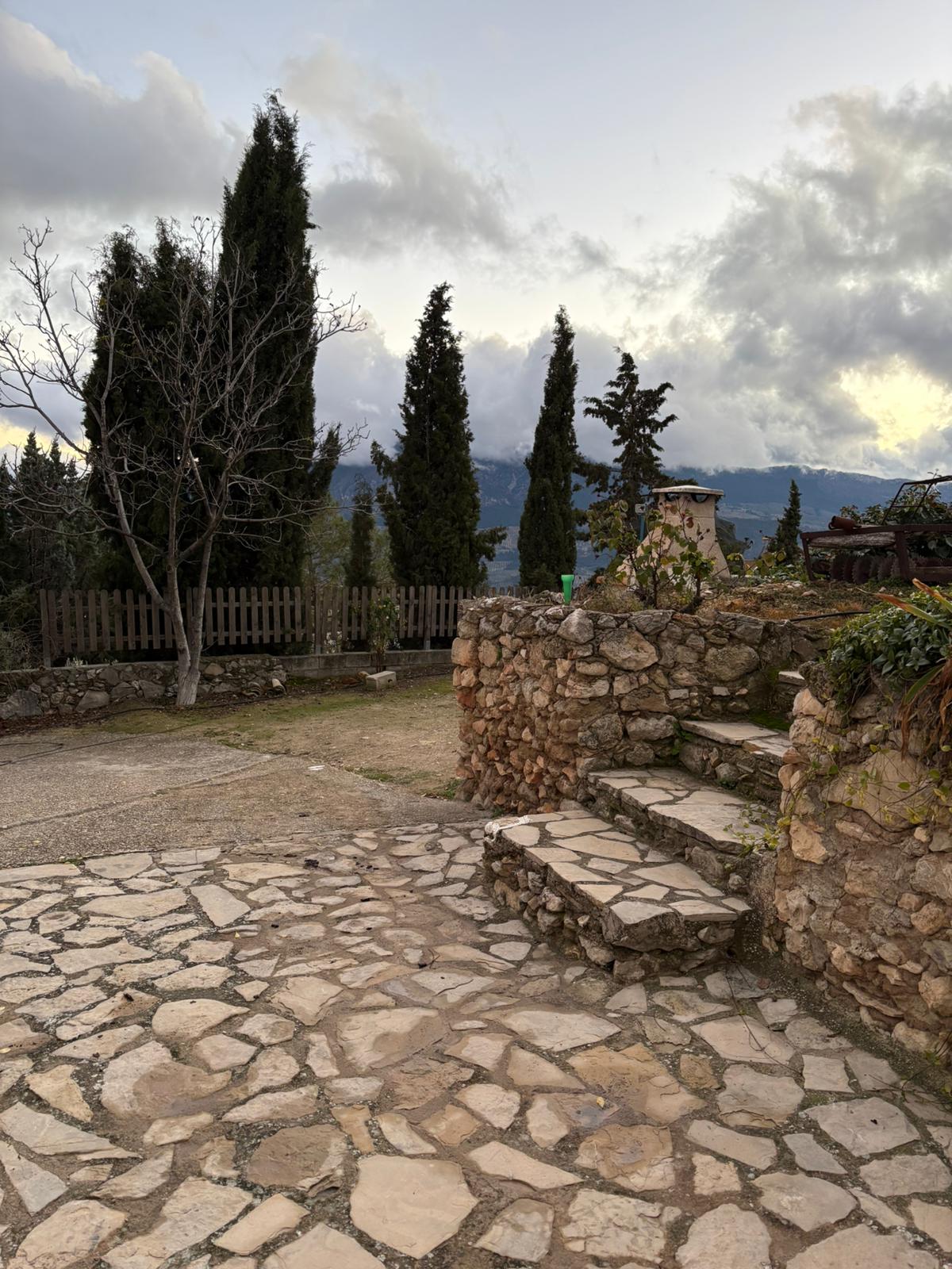 Patio exterior de piedra con pequeños desniveles y vistas abiertas hacia el paisaje de sierra. Un rincón tranquilo que invita a disfrutar del entorno al aire libre.