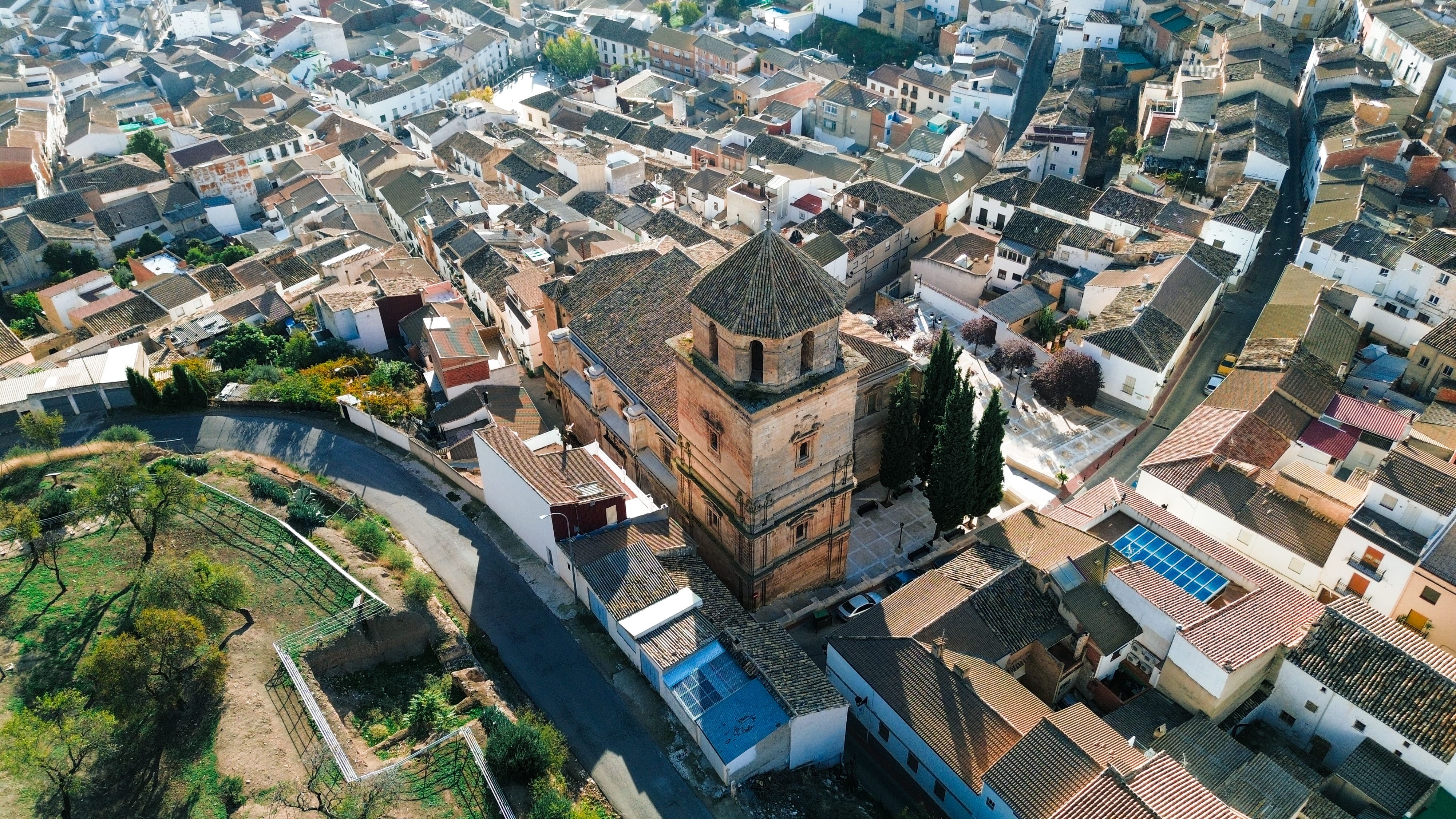 Vista aérea de un núcleo urbano de calles estrechas y casas agrupadas en torno a una iglesia de piedra con campanario. La imagen muestra la trama compacta del pueblo y el protagonismo del edificio religioso en el conjunto.