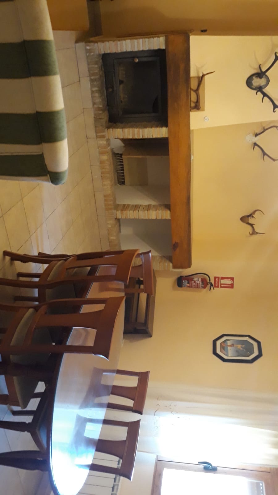 Salón-comedor con chimenea de obra y mesa amplia, ideal para reuniones en grupo. La decoración rústica y los detalles en madera aportan calidez al espacio.