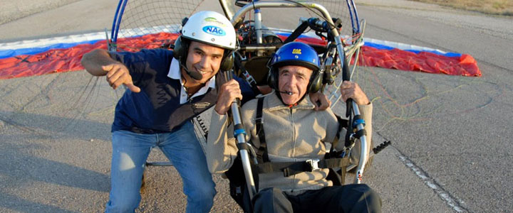 Dos participantes equipados junto a un paramotor y su vela antes de iniciar la actividad.