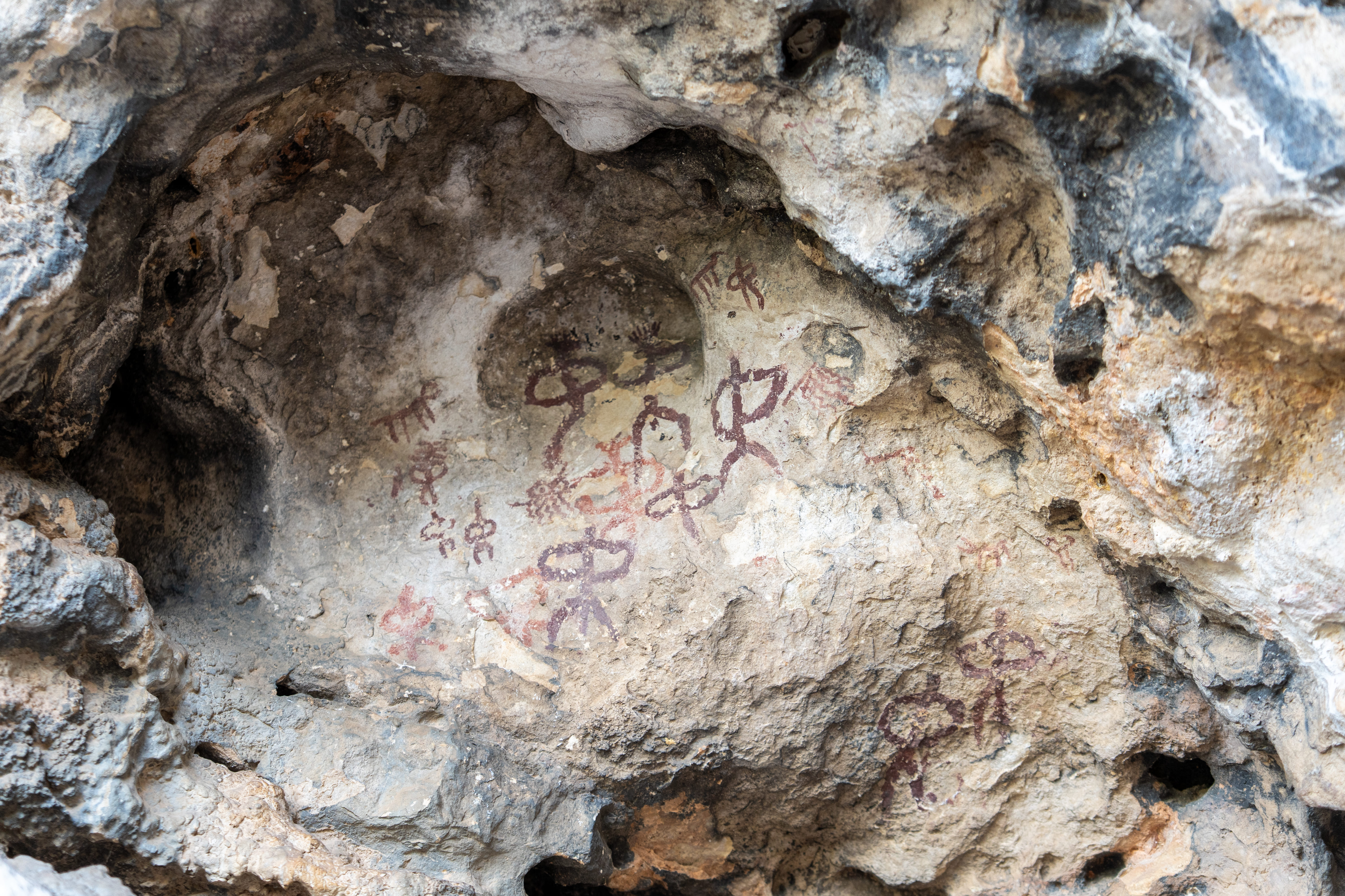 Detalle de las pinturas rupestres esquemáticas de la Cueva de la Graja en Jimena, Jaén. Estas manifestaciones artísticas, con más de 5.000 años de antigüedad, muestran figuras antropomorfas (humanas) y zoomorfas (animales) pintadas en tonos rojizos.