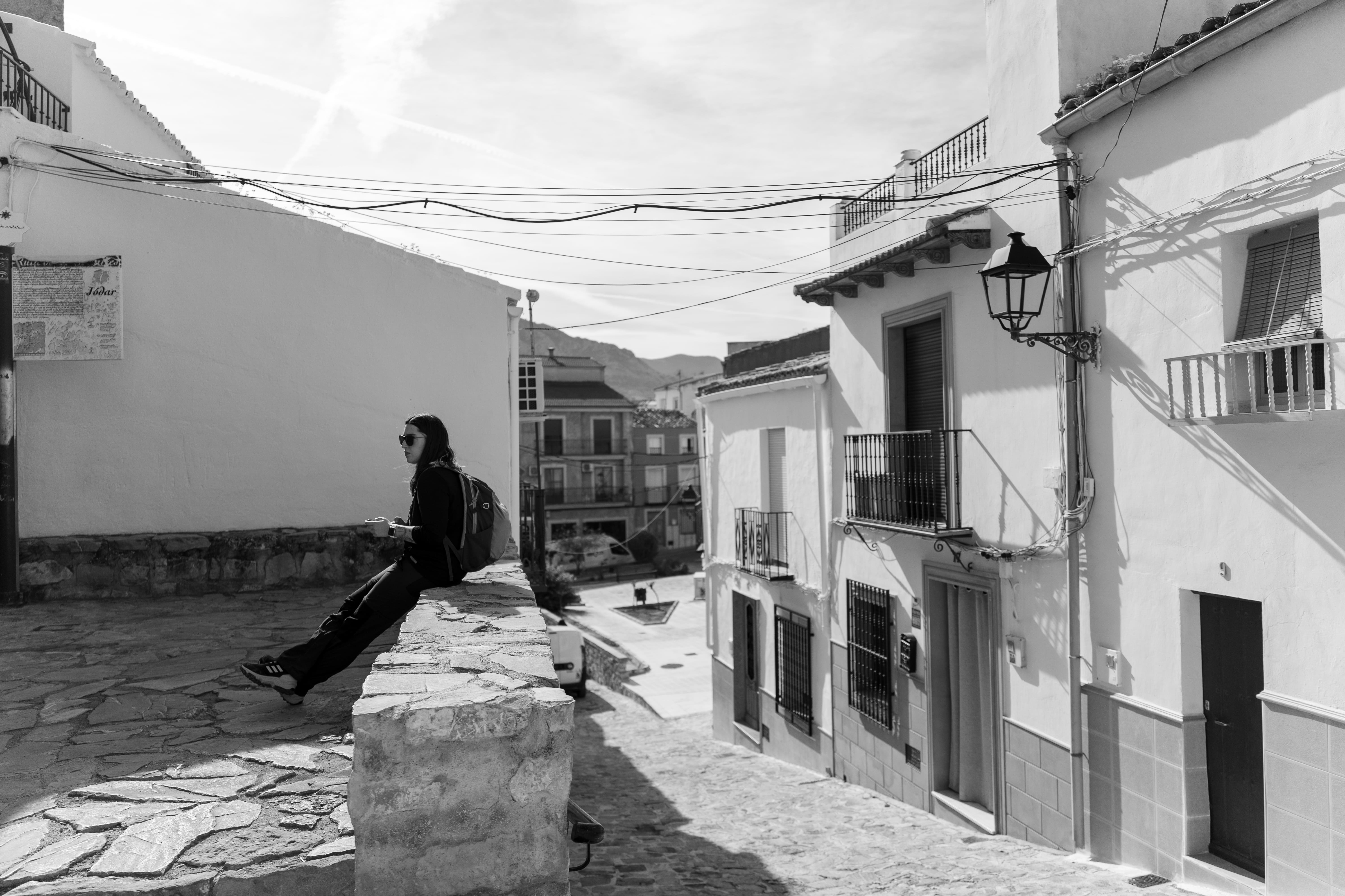 chica sentada en un muro de una calle de Jódar