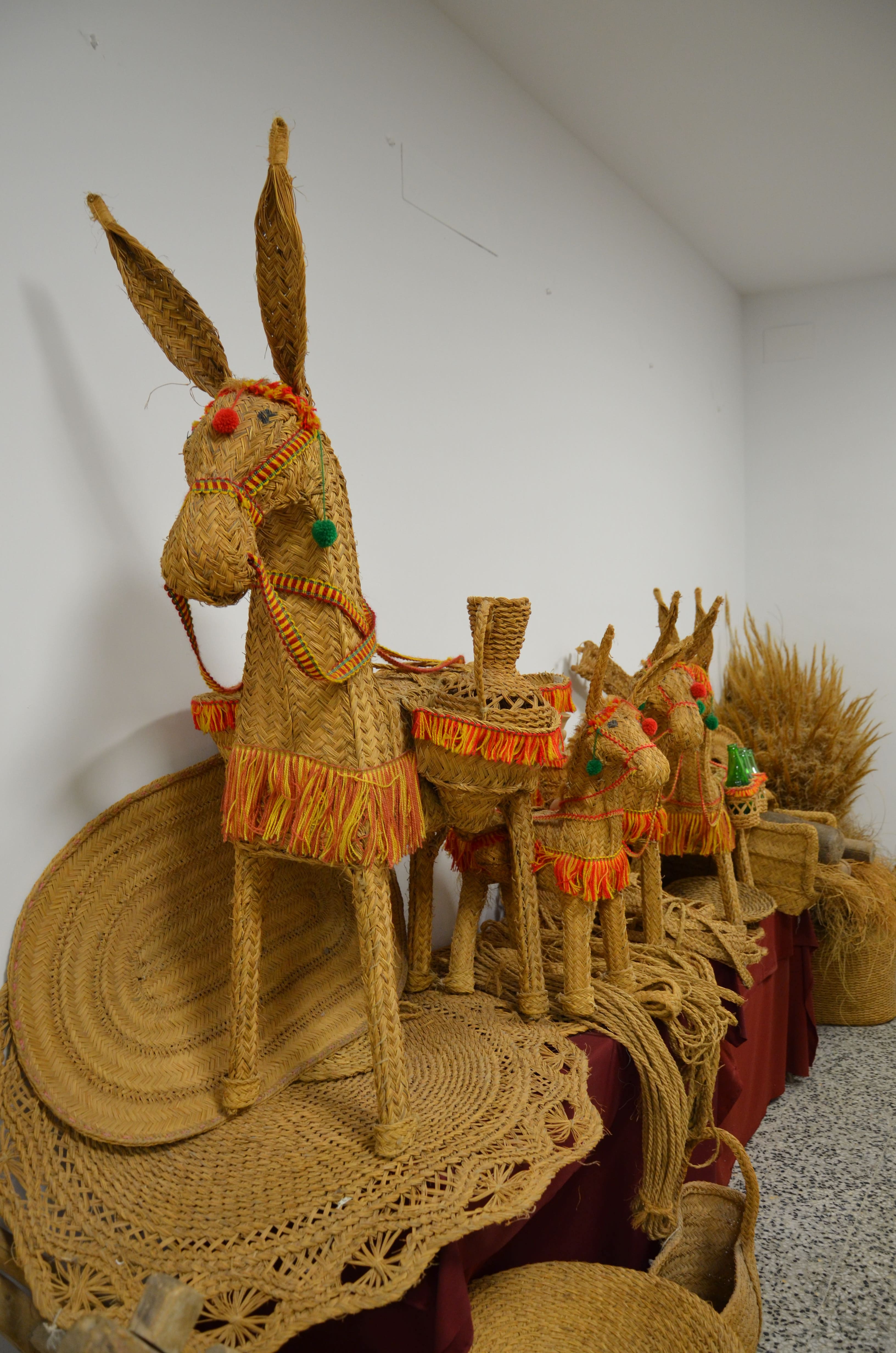 Detalle de varias figuras artesanales realizadas en esparto, con forma de burros decorados con hilos de colores. La imagen destaca el trabajo manual y la importancia de esta fibra vegetal en la artesanía tradicional.