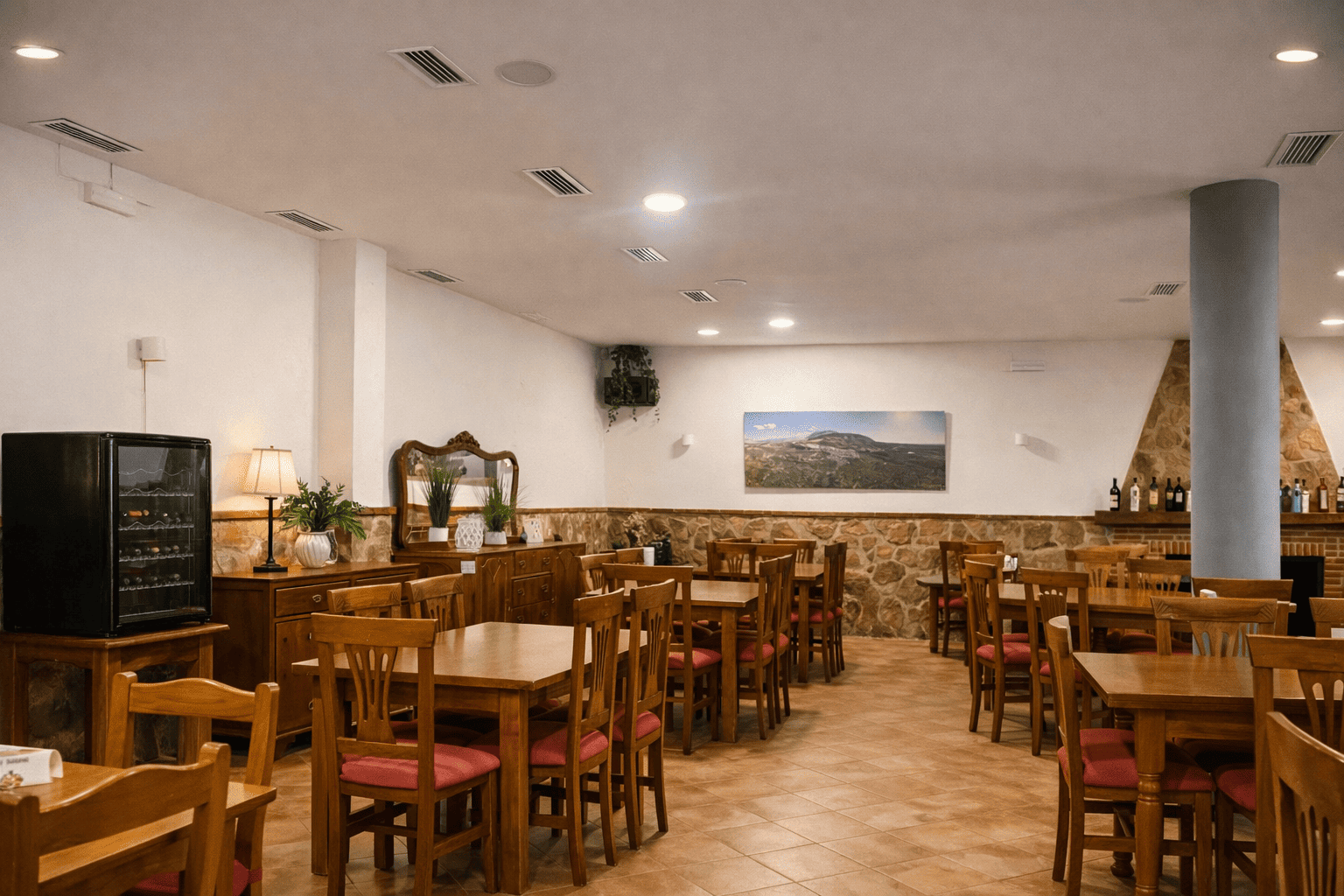 Otra vista del salón del restaurante, con mesas distribuidas en un espacio amplio y luminoso, mobiliario de madera y decoración sencilla.