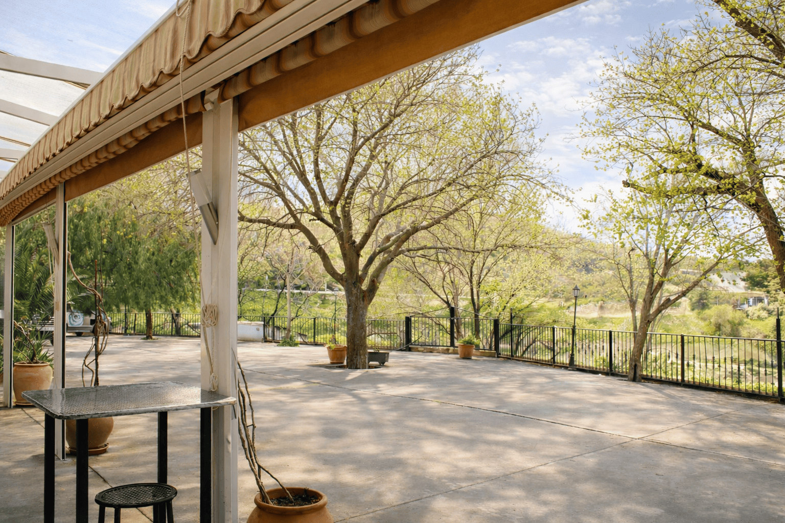 Vista exterior del restaurante con una terraza rodeada de árboles. El área está despejada y muestra el entorno natural.