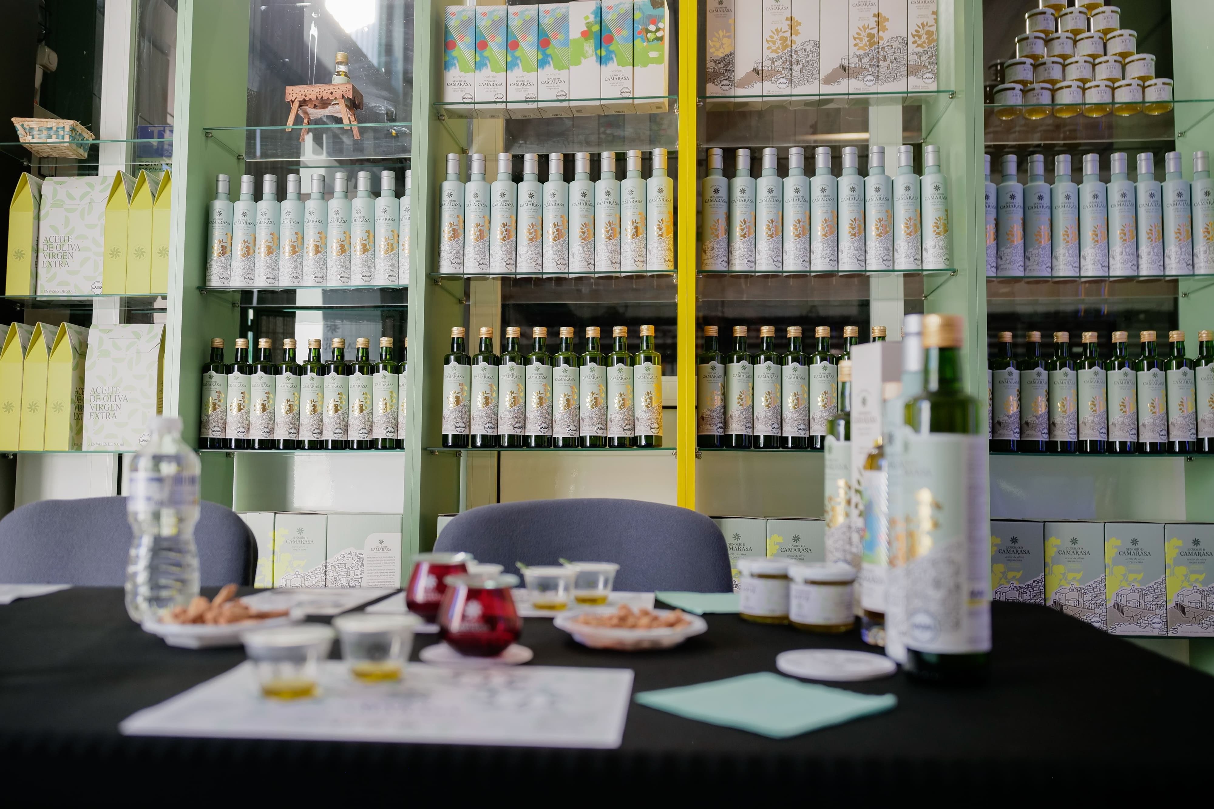 Sala preparada para una cata de aceite, con botellas de AOVE, pequeños recipientes de degustación y estanterías llenas de productos de Señorío de Camarasa al fondo.
